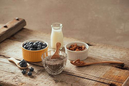 Fresh blueberries, almond and chia seeds with milk on wooden board. Ideal healthy breakfast concept.