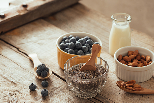 Fresh blueberries, almond and chia seeds with milk on wooden board. Ideal healthy breakfast concept.