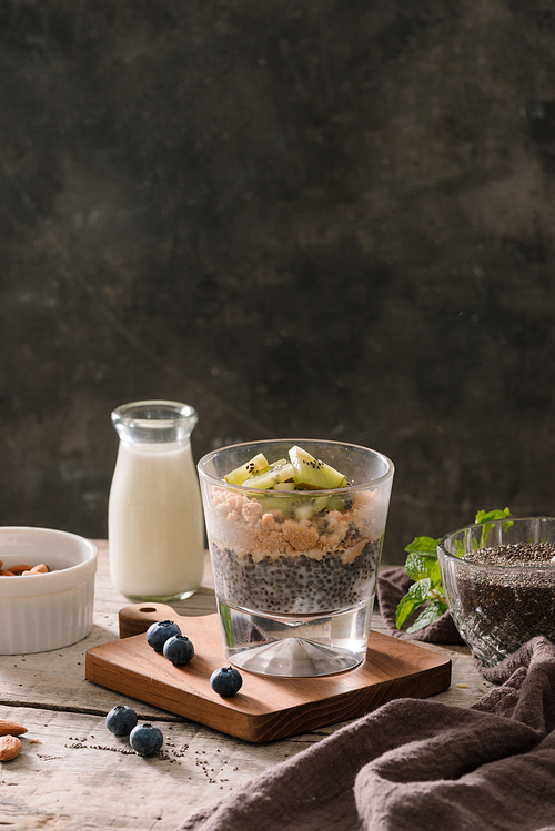 Healthy breakfast - bowl of muesli, berries and fruit, nuts, kiwi, milk
