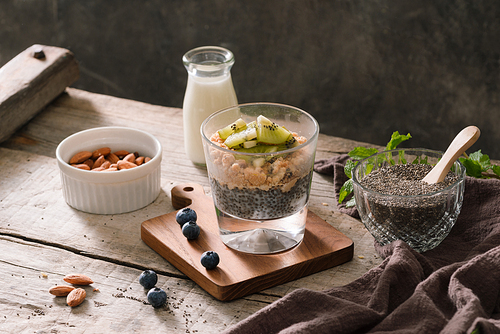 Healthy breakfast - bowl of muesli, berries and fruit, nuts, kiwi, milk