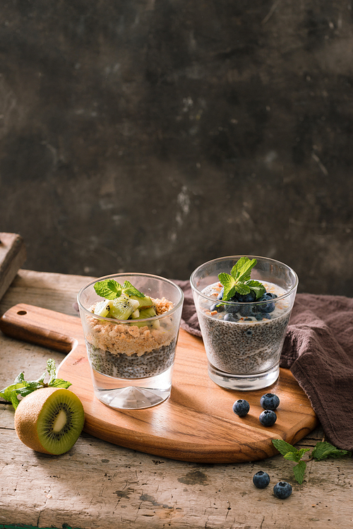 Healthy breakfast - bowl of muesli, berries and fruit, nuts, kiwi, milk