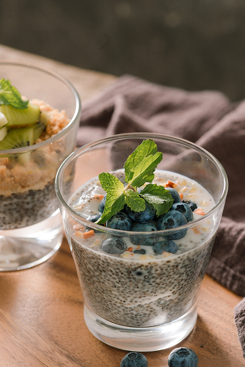 Healthy breakfast - bowl of muesli, berries and fruit, nuts, kiwi, milk