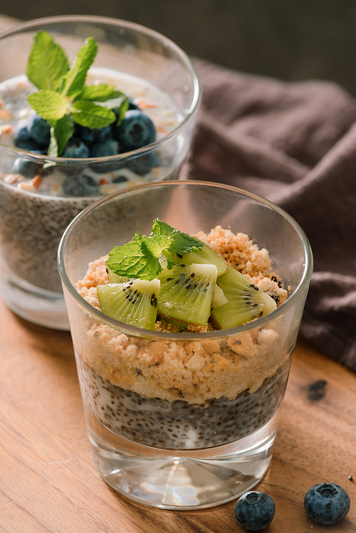 Healthy breakfast - bowl of muesli, berries and fruit, nuts, kiwi, milk