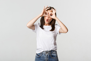 Silly cute brunette girl making hand glasses and showing funny faces.