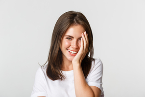 Close-up of beautiful smiling woman looking coquettish at camera over white background.