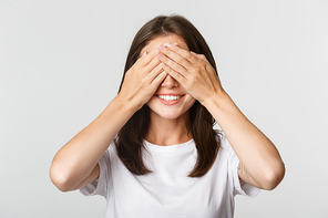 Portrait of smiling excited brunette girl close eyes and waiting for surprise.