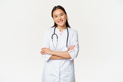 Asian female doctor, physician in medical uniform with stethoscope, cross arms on chest, smiling and looking like professional, white background.