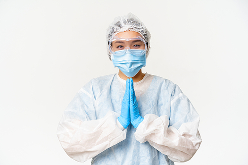 Please vaccinate. Smiling asian female doctor or nurse in personal protective equipment, showing beg, asking gesture, standing over white background.