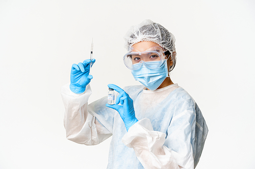 Asian doctor or nurse in medical protective equipment, looking confident at camera, holding syringe and vaccine from covid-19, vaccination campaign and medical concept.