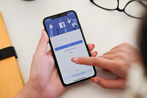CHIANG MAI ,THAILAND - JAN 19, 2020 : Woman hand holding iPhone XS to use facebook with new login screen.Facebook is a largest social network and most popular social networking site in the world.