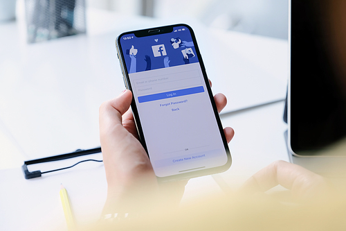 CHIANG MAI ,THAILAND - MAR 7, 2020 : Woman hand holding iPhone XS to use facebook with new login screen.Facebook is a largest social network and most popular social networking site in the world.