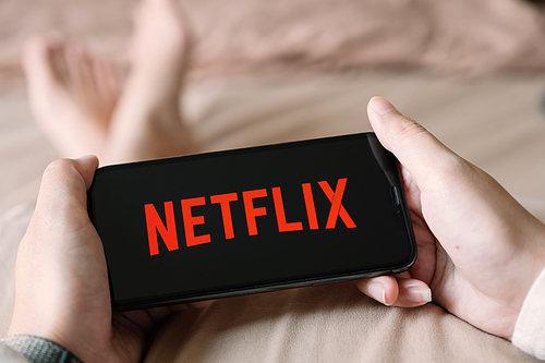 CHIANG MAI,THAILAND - APR 06, 2020 : Woman  using iPhone X open Netflix application at home. Netflix is a global provider of streaming movies and TV series.