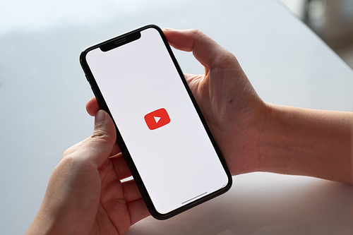 CHIANG MAI, THAILAND - NOV.17 ,2019: Woman holding iPhone Xs with Youtube apps on screen. YouTube is the popular online video sharing website.