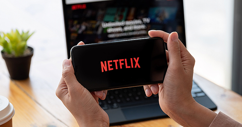 CHIANG MAI,THAILAND - MAR 21, 2021 : Woman using iPhone X open Netflix application at home. Netflix is a global provider of streaming movies and TV series.