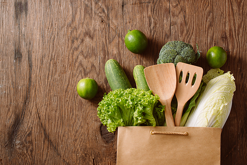 top view of green vegetables in shopping bag on wooden table