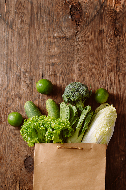 top view of green vegetables in shopping bag on wooden table