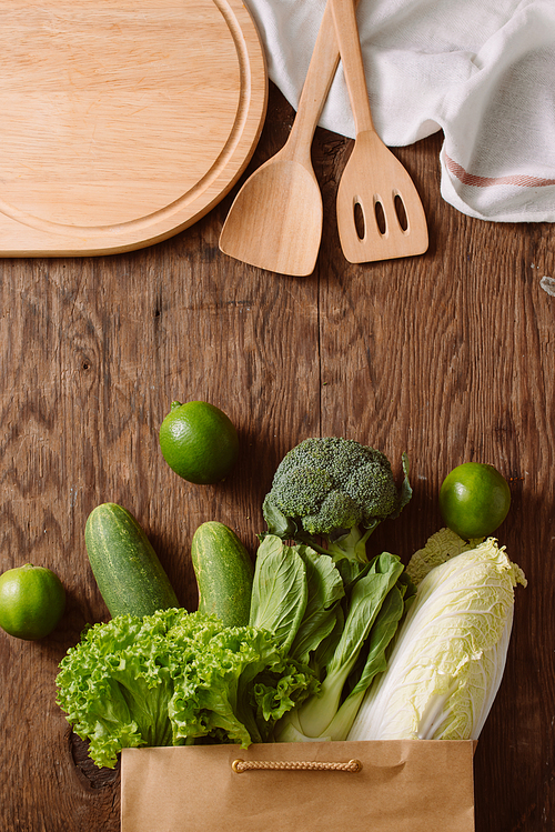 top view of green vegetables in shopping bag on wooden table