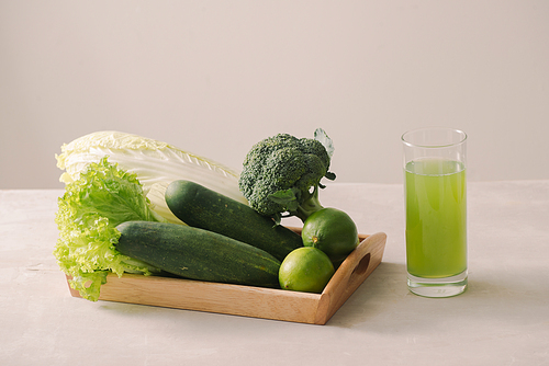 Vegan diet food. Detox drinks. Freshly squeezed juices and smoothies from vegetables. On white background, wooden tray, ingredients. Copy space