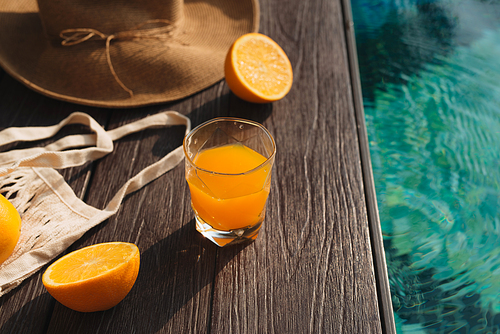 Beach hat, orange juice and sunglasses near the swimming pool