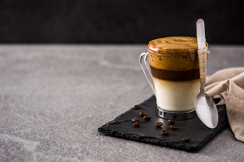 Creamy iced dalgona coffee on gray stone background