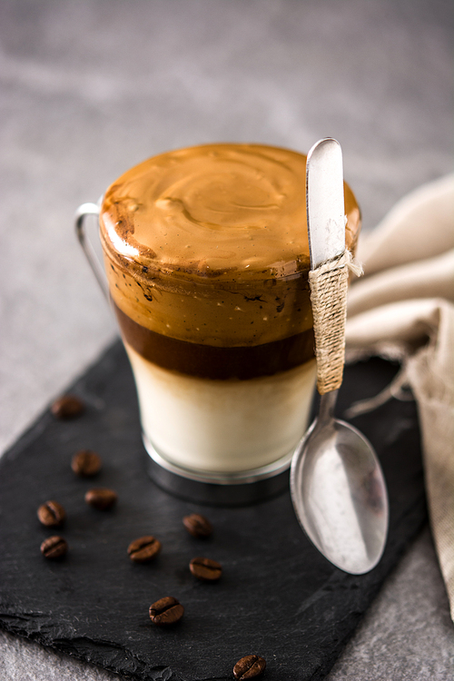 Creamy iced dalgona coffee on gray stone background