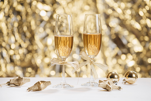 Two full champagne glasses with bokeh lights in the background