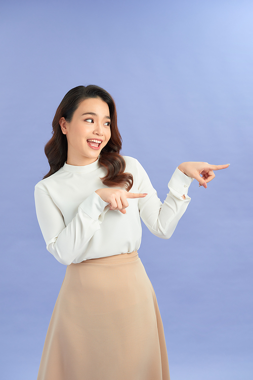 Young asian woman isolated on purple background shocked pointing with index fingers to a copy space.