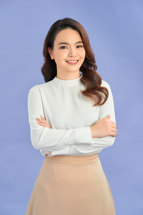 portrait of pretty asian girl smiling with arm crossed on purple background