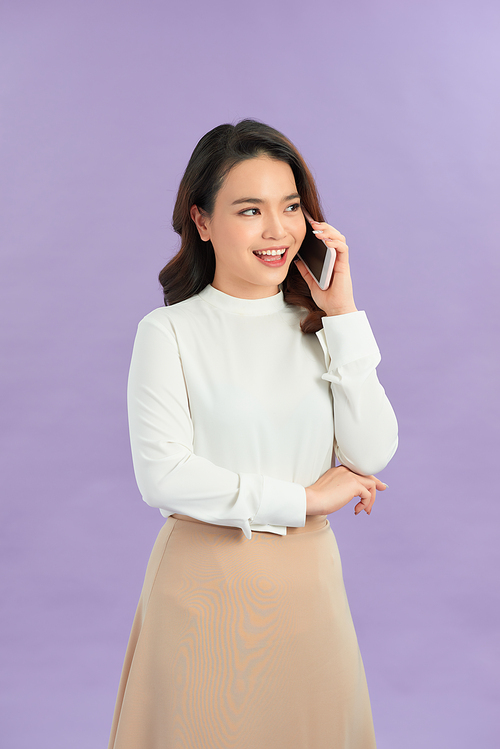Portrait of a smiling young casual asian girl talking on mobile phone