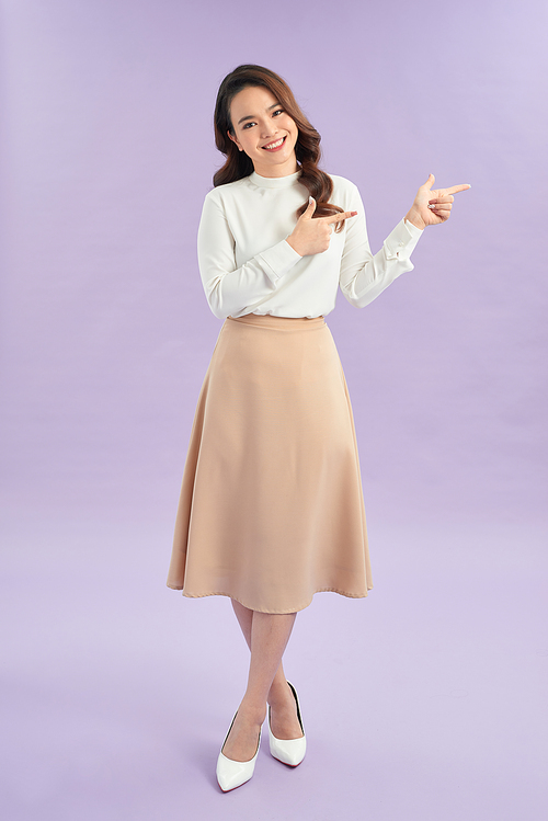 Young woman pointing finger to the side on isolated purple background