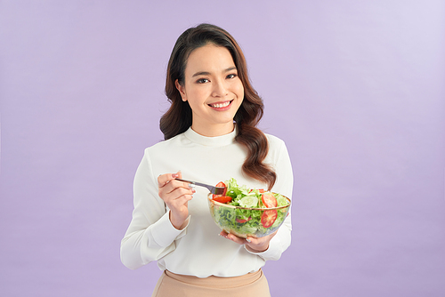 Young asian woman beaming while eating fresh salad