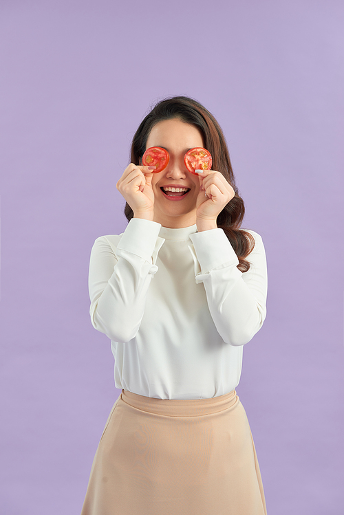 Attractive Asian woman covering her eyes with tomato slice . Healthy and beauty skin care concept.