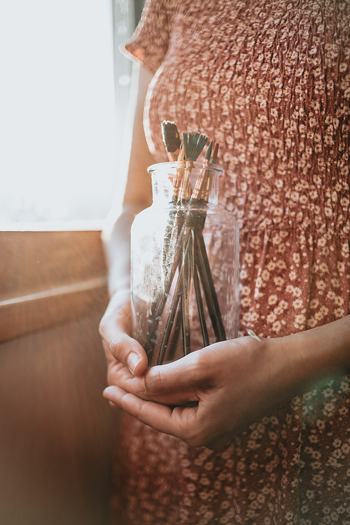 Young woman artist hands grabbing a bottle filled with paint pencils and brushes, ready for painting acrylic. Artistic concepts, artist concept. Beauty dress concept vintage with sun bean, copy space