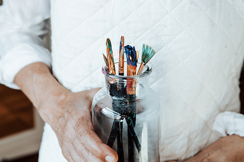 Woman artist painter holding a bunch of paint brush. Painter artist and paintbrush in studio, Crystal bottle, indie style, hipster, creative concept