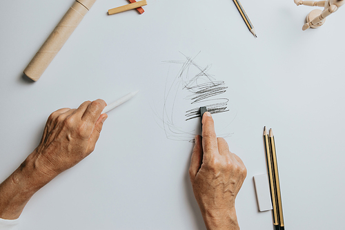 High angle view of a senior Caucasian woman drawing sketches in studio. Creativity, education and people concept,cognitive functions clock drawing self assessment test at home with positive results