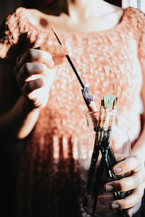 Woman artist painter holding a bunch of paint brush. Painter artist and paintbrush in studio, Crystal bottle, indie style, hipster, creative concept