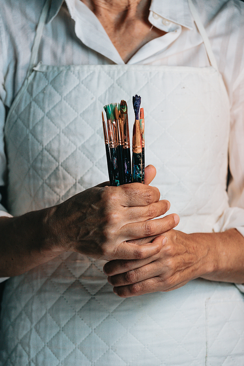 Woman artist painter holding a bunch of paint brush. Painter artist and paintbrush in studio, Crystal bottle, indie style, hipster, creative concept