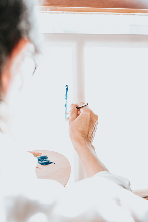 Close up of paintbrush painting in blue color in a canvas. Colorful image from an artist’s studio or a school showing creative education