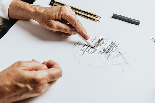 High angle view of a senior Caucasian woman drawing sketches in studio. Creativity, education and people concept,cognitive functions clock drawing self assessment test at home with positive results