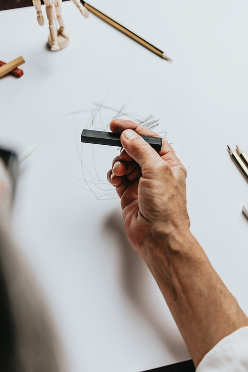 High angle view of a senior Caucasian woman drawing sketches in studio. Creativity, education and people concept,cognitive functions clock drawing self assessment test at home with positive results