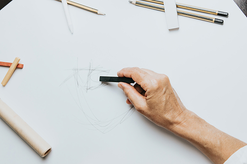 High angle view of a senior Caucasian woman drawing sketches in studio. Creativity, education and people concept,cognitive functions clock drawing self assessment test at home with positive results