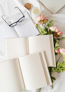 Blank opened books and flowers on white bed, flat lay, mock up, flat lay