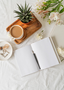 Blank opened book, coffee , flowers on white bed, flat lay, mock up, flat lay