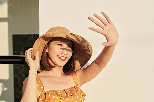 Portrait of a beautiful Asian girl covering face by hand of bright sun light, happy summer vacation