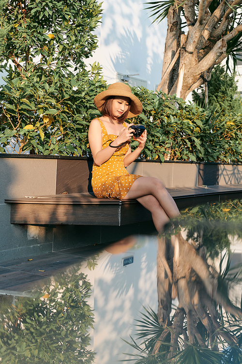 smiling young Asian woman using a camera to take photo outdoors at the park