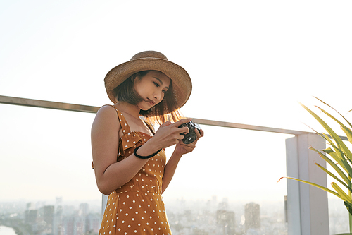 Young beautiful Asian traveler woman using digital compact camera and smile