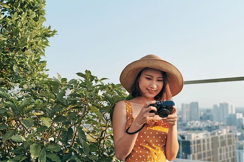 Young Asian girl standing on roof top and using camera to take picture. Summer concept.