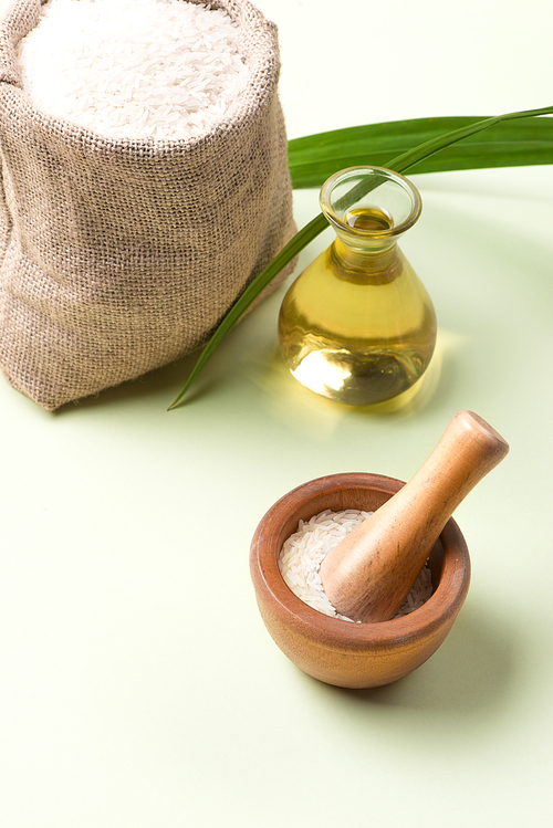 Rice bran oil in a glass and jar with uncooked jasmine rice