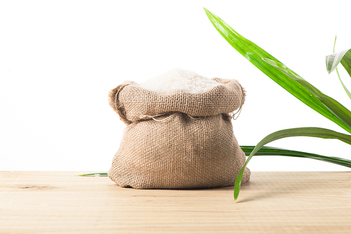 white rice in burlap sack with green leaves