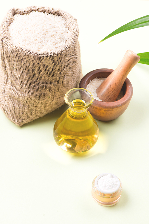 Rice bran oil extract and brown rice on wood table background.